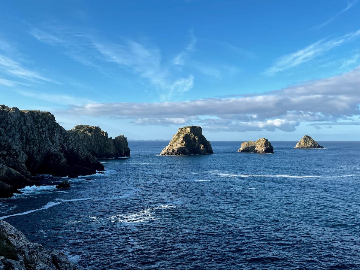 Rochers imposants dans l'océan atlantique, sous un ciel bleu avec quelques nuages.